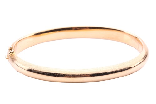 Lot 145 - A yellow metal bangle; brushed finish, with a...