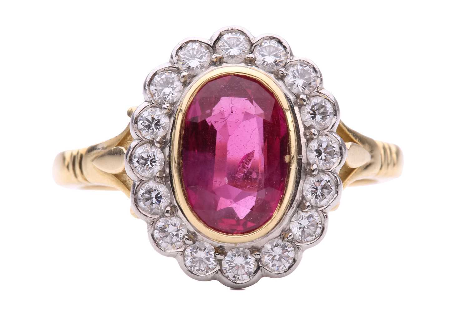 Lot 69 - A ruby and diamond halo ring, centred with an...