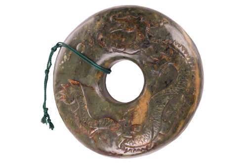 Lot 107 - A Chinese carved moss variegated jade Bi disk...