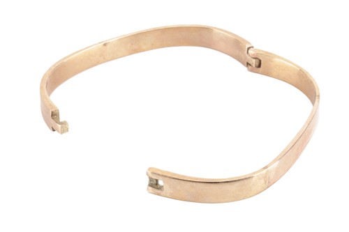 Lot 95 - A hinged bangle in 9ct yellow gold, of angular...