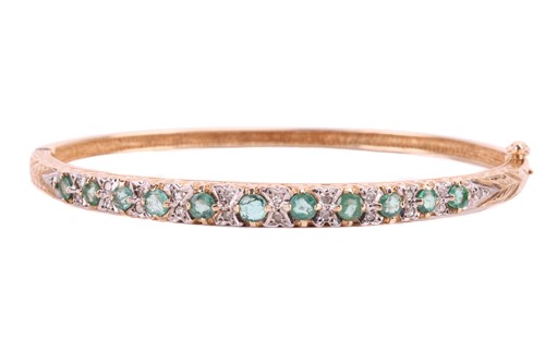 Lot 102 - An emerald and diamond bangle, set with a row...