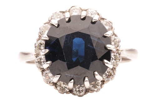 Lot 44 - A sapphire and diamond halo ring in 18ct white...