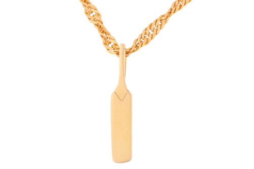 Lot 24 - A cricket bat pendant on chain, on a flat curb...