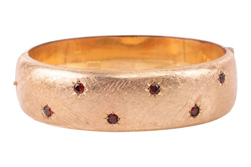 Lot 40 - A gold and garnet hinged bangle, the brushed...