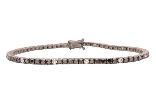 Lot 72 - A diamond line bracelet, set with black...