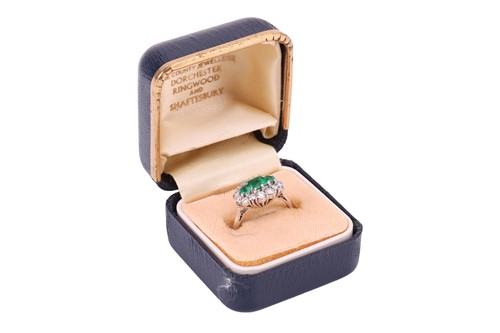 Lot 45 - An emerald and diamond cluster ring in 18ct...