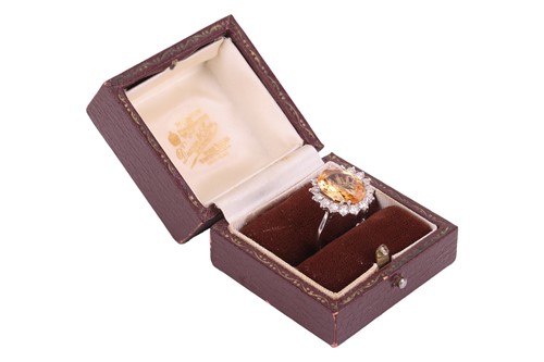 Lot 19 - A topaz and diamond halo ring, centred with an...