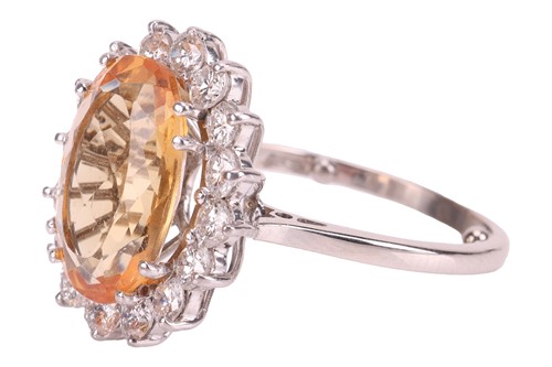 Lot 19 - A topaz and diamond halo ring, centred with an...
