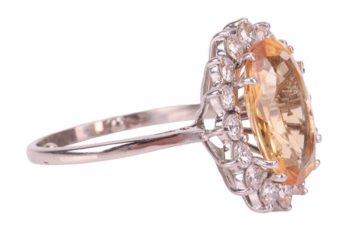 Lot 19 - A topaz and diamond halo ring, centred with an...