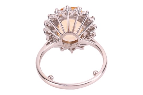 Lot 19 - A topaz and diamond halo ring, centred with an...