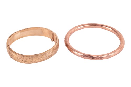 Lot 74 - A hinged oval bangle with scrollwork detailing,...