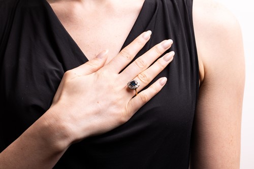 Lot 28 - A sapphire and diamond cluster ring, centred...