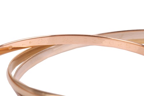 Lot 232 - Cartier – a trinity bangle in 18ct gold,...