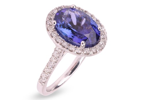 Lot 306 - A tanzanite and diamond halo ring in platinum,...