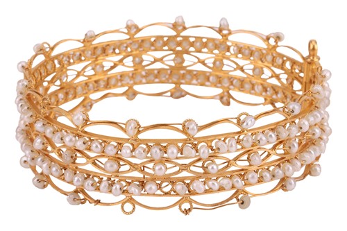 Lot 273 - An open-work bangle set with seed pearls; the...