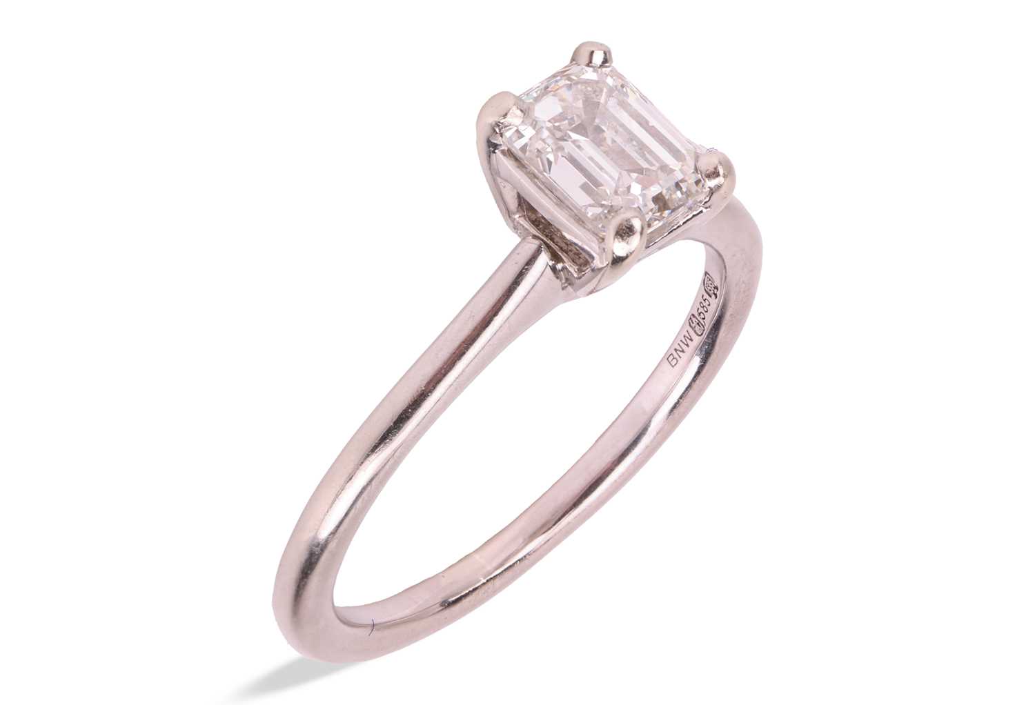 Lot An emerald-cut diamond solitaire ring in 14ct...