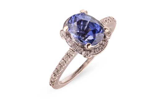 Lot 332 - A sapphire and diamond halo ring in 18ct white...
