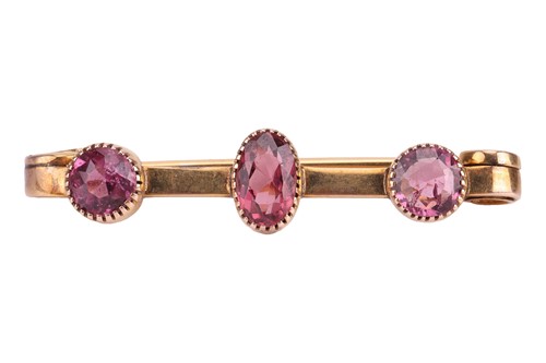 Lot A garnet-set bar brooch, collet-set with an...