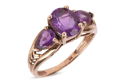Lot 95 - An amethyst trilogy ring, centred with an oval-...