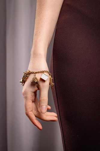 Lot 125 - A 9ct gold charm bracelet, composed of a curb...