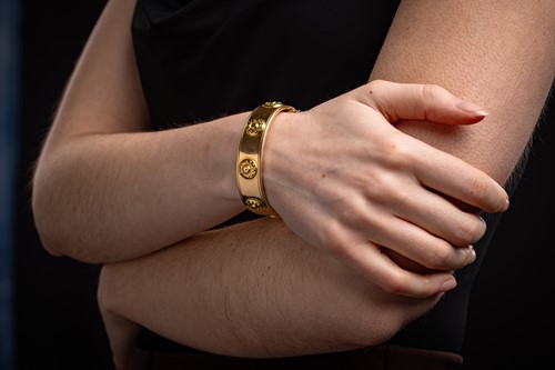 Lot 210 - A hollow hinged bangle, the wide band...
