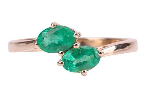 Lot 62 - An emerald-set crossover-style ring, with two...
