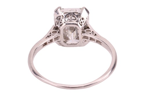 Lot An emerald-cut diamond solitaire ring, the...