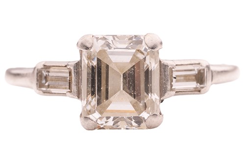 Lot An emerald-cut diamond solitaire ring,...
