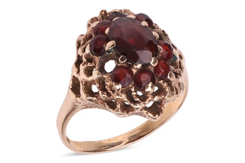 Lot 62 - A garnet-set cluster ring, the central oval...