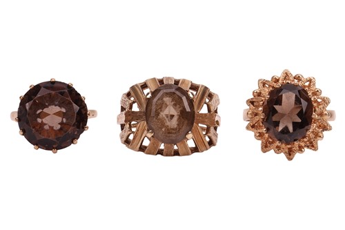Lot 59 - Three smoky quartz rings, featuring a claw-set...