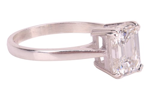 Lot An emerald-cut diamond solitaire ring,...