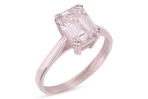 Lot An emerald-cut diamond solitaire ring,...