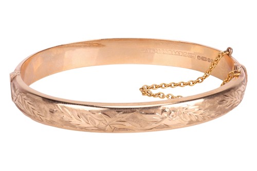 Lot 67 - A 9ct gold bangle, with foliate engraving...