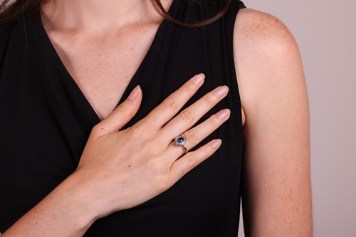 Lot 135 - A sapphire & diamond cluster ring, featuring a...